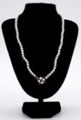 A 20 inch graduated and knotted cultured pearl necklace. The necklace is strung with seventy six