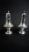 A pair of Victorian sterling silver weighted salt and pepper shakers with flame design finials and