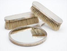 A sterling silver vintage three piece brush and mirror set, each with engine turned decoration.
