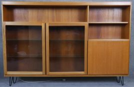 A vintage McIntosh teak bookcase cabinet with interior light standing on metal hairpin supports with