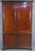 An early 19th century mahogany estate cabinet, the dentil cornice above fielded panel doors