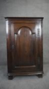 A Georgian country oak corner cabinet with fielded panel door enclosing shaped shelves on block