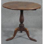 A Georgian oak tilt top table on baluster pedestal tripod supports. H.75cm (top in need of some