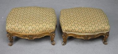 A pair of late 19th century carved giltwood footstools in tapestry upholstery on squat Rococo carved