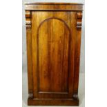An early Victorian rosewood pier cabinet with arched panel door enclosing shelves on plinth base.