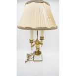 A gilt metal twin branch table lamp with cherub base holding flames aloft. H.64cm