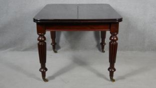 A William IV style mahogany extending dining table with two extra leaves on reeded tapering supports