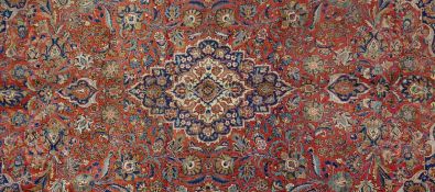 A Persian Keshan carpet with central medallion and naturalistic floral design across the burgundy