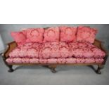 A mid century mahogany Georgian style bergere sofa with caned back and sides on squat cabriole