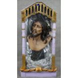 A plaster bust of Jesus Christ within a glass display case with gilded detailing and painted. H.84cm