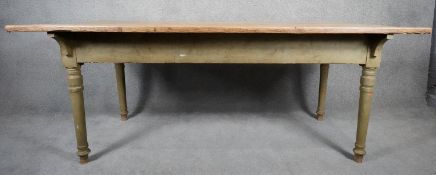 A 19th century ash planked top kitchen dining table on original green painted turned tapering