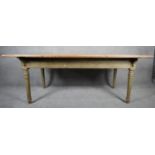 A 19th century ash planked top kitchen dining table on original green painted turned tapering