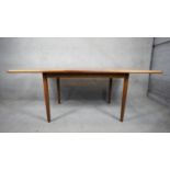 A 1960's vintage Meredew teak dining table with integral fold out central leaf and maker's label