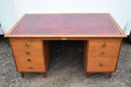 A mid century teak desk with inset tooled leather top above twin pedestals.