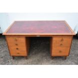 A mid century teak desk with inset tooled leather top above twin pedestals.