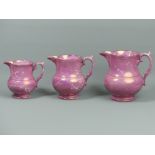 A graduated set of three 19th century Sunderland pink lustre pottery jugs. Tallest 15 cm. UK Postage