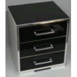 A black glass, chrome and silver chest of three drawers. 48 cm wide x 42 cm deep x 55 cm high.