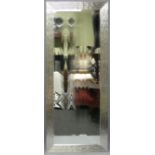 A large bevelled glass wall mirror in a wave design silvered frame. 79 x 186 cm.