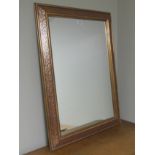 A maroon and gilt framed bevelled glass mirror. 77 x 106 cm. Collection only.