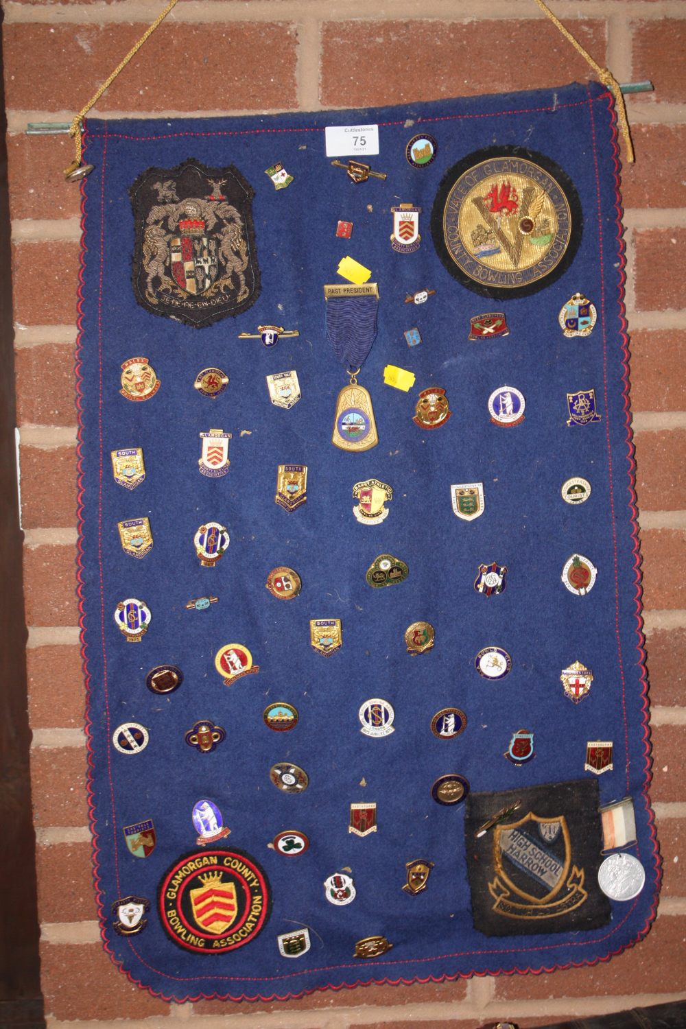 A WALL MOUNTED PENDANT DISPLAY OF WELSH BADGES AND MEDALS ETC