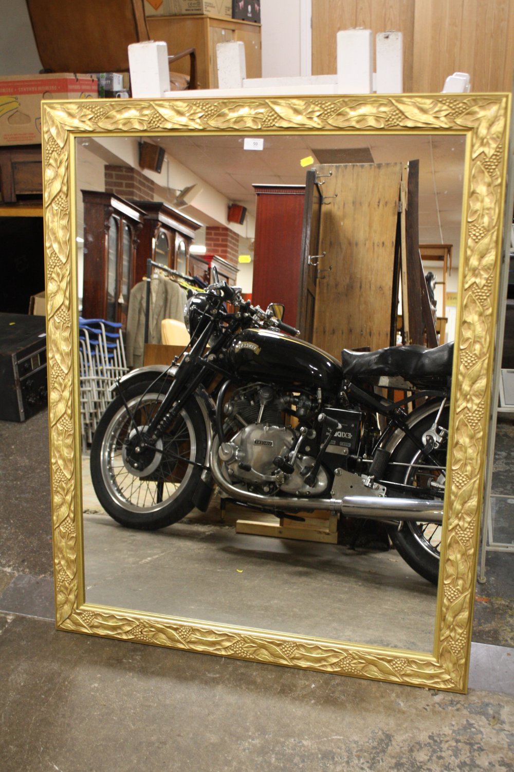 A LARGE GILT FRAME WALL MIRROR WITH RELIEF DETAIL TO THE FRAME, OVERALL SIZE INC FRAME 98.5CM X