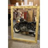 A LARGE GILT FRAME WALL MIRROR WITH RELIEF DETAIL TO THE FRAME, OVERALL SIZE INC FRAME 98.5CM X