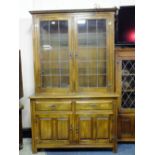 A SOLID OAK GLAZED BOOKCASE WITH TWO DRAWERS AND CUPBOARDS BELOW H-189 W-118 CM