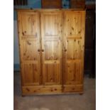 A PINE TRIPLE DOOR, THREE DRAWER WARDROBE