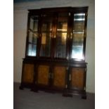 A GLASS SHELVED MIRROR BACKED BREAKFRONT WALL UNIT