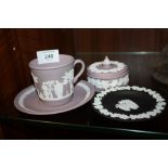 A WEDGWOOD LILAC JASPERWARE CUP AND SAUCER AND TRINKET BOWL, TOGETHER WITH A BLACK JASPERWARE PIN