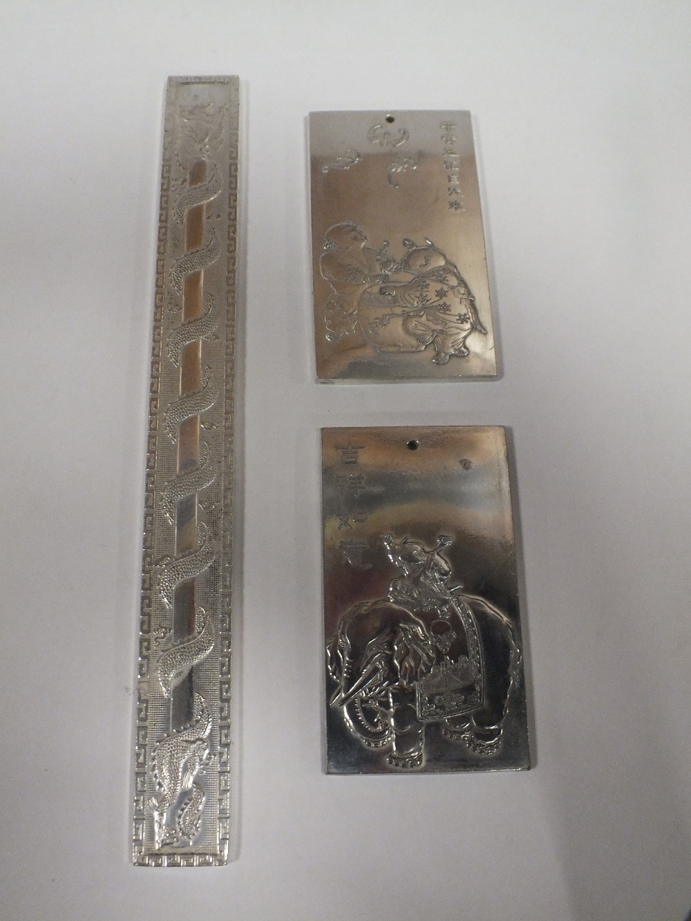 THREE ORIENTAL WHITE METAL SCROLL WEIGHTS