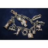 A SILVER CHARM BRACELET WITH ASSORTED CHARMS - APPROX 54.1G