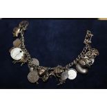 A SILVER CHARM BRACELET WITH ASSORTED CHARMS - APPROX 64.2G