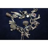 A SILVER CHARM BRACELET WITH ASSORTED CHARMS - APPROX 54.7G