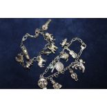 A SILVER CHARM BRACELET WITH ASSORTED CHARMS - APPROX 48.3G