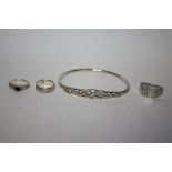 A STERLING SILVER BANGLE AND THREE SILVER DRESS RINGS