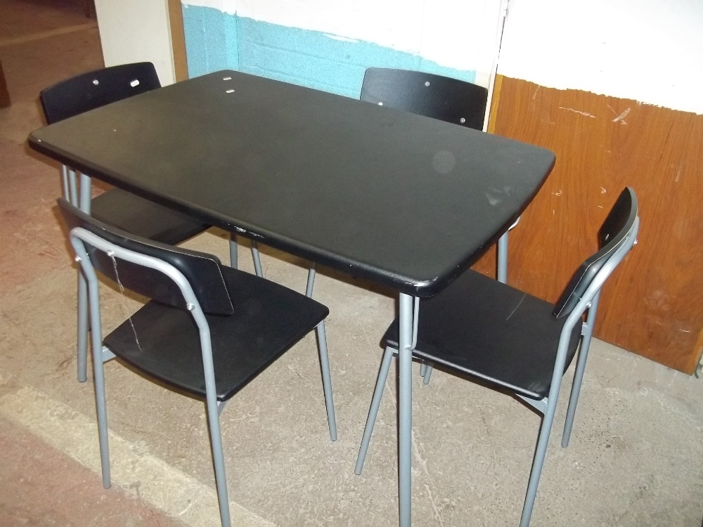 A BLACK DINING TABLE AND FOUR STACKABLE CHAIRS