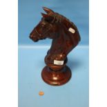 A CARVED WOODEN HORSE'S HEAD ON PLINTH