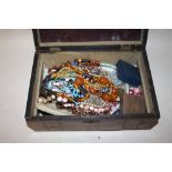 AN INLAID MAHOGANY LIDDED BOX CONTAINING COSTUME JEWELLERY TO INCLUDE AN AMBER STYLE NECKLACE