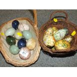 A BASKET OF POLISHED HARD STONE EGGS TOGETHER WITH TWO BASKETS OF HAND PAINTED WOODEN EGGS