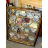 A WALL HANGING OAK LEADED GLAZED DISPLAY CASE CONTAINING VINTAGE JARS AND TINS, S/D