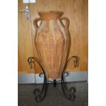 A LARGE TWIN HANDLED TERRACOTTA VASE ON CAST METAL STAND OVERALL HEIGHT - 93CM