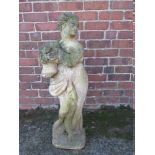 A STONE GARDEN 'SPRING' FIGURE, depicting a lady holding a basket of flowers, H 87.5 cm