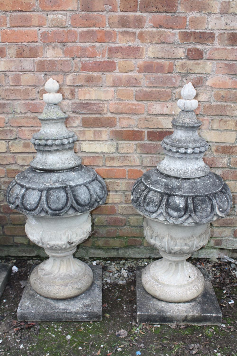 A PAIR OF LARGE STONE PEDESTAL URNS, supported on a squared foot leading to a solid swirling base,