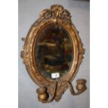 AN ANTIQUE GILT FRAMED OVAL MIRROR WITH SCONCES - OVERALL SIZE - 48 CM X 34CM