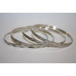 A SET OF FOUR VINTAGE SILVER ENGRAVED BANGLES - APPROX 32G