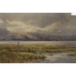 A FRAMED AND GLAZED WATERCOLOUR DEPICTING A MOUNTAINOUS RIVER LANDSCAPE WITH SHEEP GRAZING SIGNED