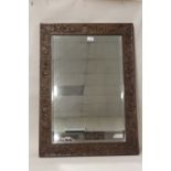 AN OAK FRAMED MIRROR WITH FLORAL CARVED DETAIL - OVERALL SIZE 81 CM BY 59 CM