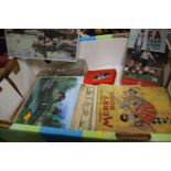 A TRAY OF TWO UNOPENED 1000 PIECE JIGSAWS, VINTAGE BOOKS, BOXED POCKET BINOCULARS AND GLASSWARE