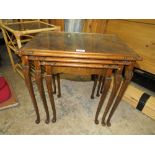 A WALNUT GLASS TOPPED NEST OF TABLES